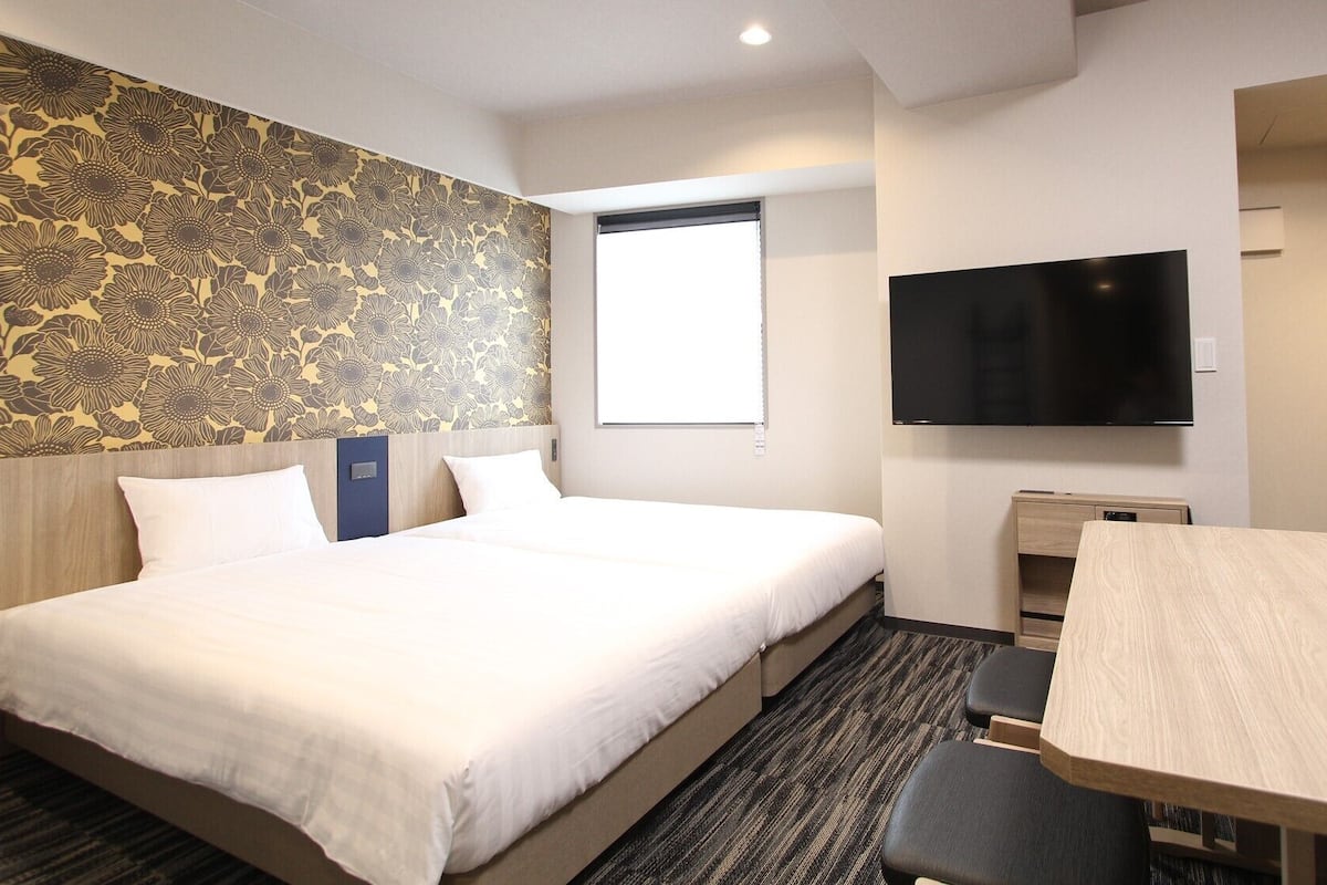 Une chambre d’hôtel avec un grand lit, un bureau, un téléviseur à écran plat et une fenêtre.