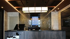 A hotel reception desk with a modern design, a digital screen displaying the hotel name, and a seating area. - KOKO HOTEL Residence Asakusa Tawaramachi (Tokyo)