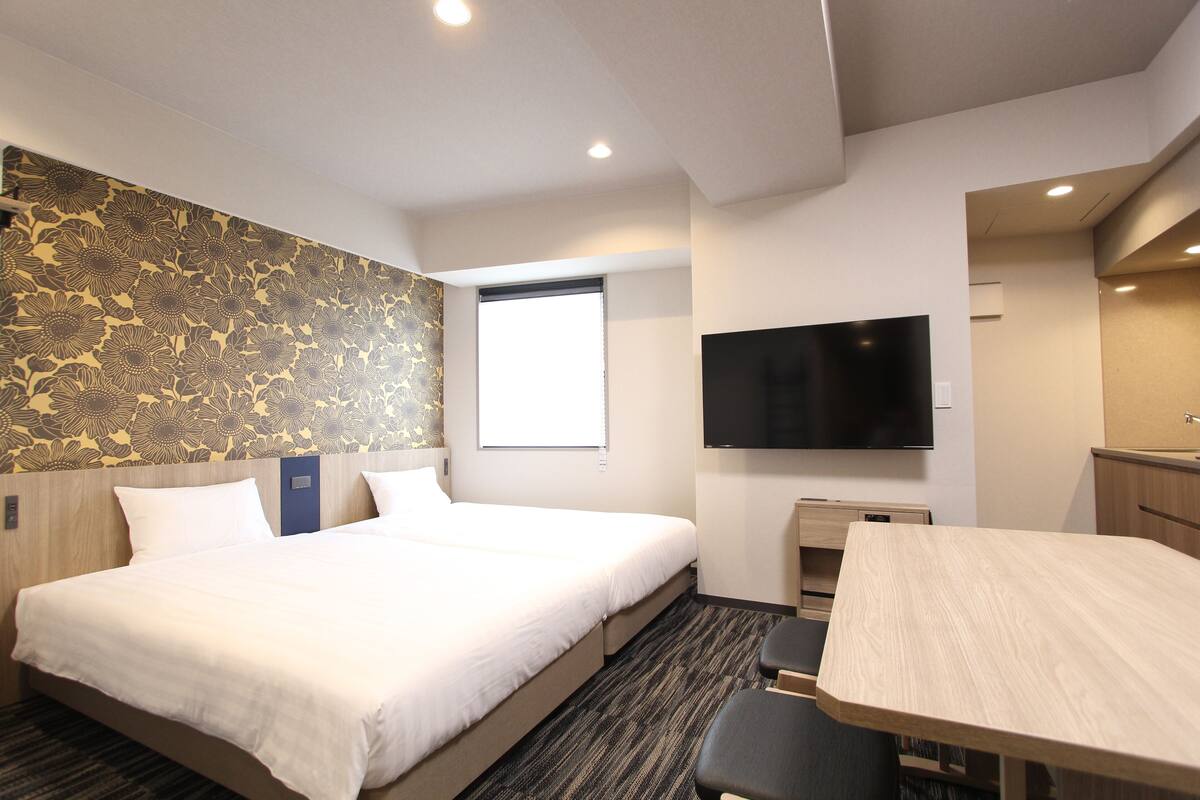 Ein Hotelzimmer mit einem großen Bett, einem Schreibtisch, einem Flachbildfernseher und einem Fenster.