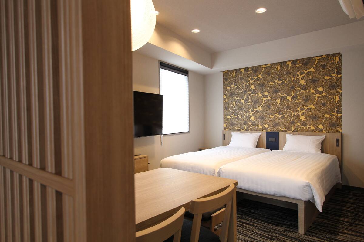 Ein Hotelzimmer mit zwei Betten, einem Holztisch und einem Fernseher.