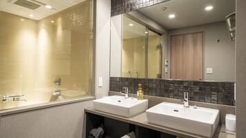 A modern bathroom with two sinks, a large mirror, and a shower area.