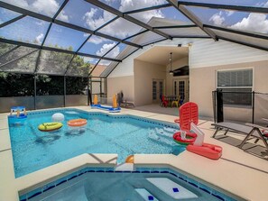 Ein Schwimmbad mit Glasdach, umgeben von einer Terrasse mit Stühlen und einem Tisch.