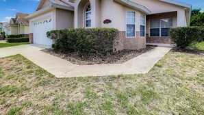 A two-story house with a garage, a front porch, and a well-maintained lawn. - Single Level 5 Bedrm/Pool/SPA/3Miles Disney (Kissimmee)