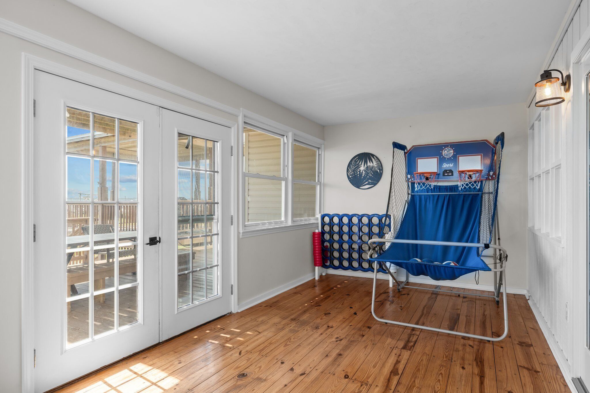 A room with wooden flooring, white walls, and a basketball hoop.