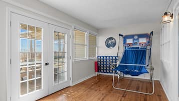 A room with wooden flooring, white walls, and a basketball hoop.