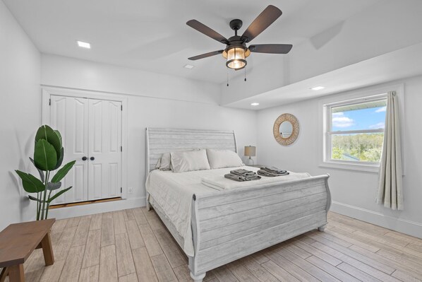 A bedroom with a bed, a ceiling fan, a window with a view, a door, and a plant. - Shell Hill house Waterfront, kayaks, grill, pier (Sealevel)
