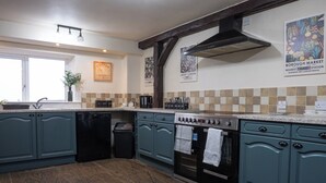 Una cucina con mobili color petrolio, lavastoviglie, forno e angolo caffè.