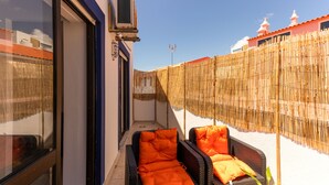A balcony with wicker furniture and a bamboo fence. - Charming 2-Bed Apartment in Armacao de Pera (Armacao de Pera)