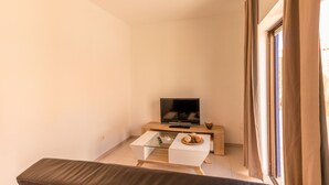 A small, modern room with a glass-top coffee table, a flat-screen TV, and a wooden side table. - Charming 2-Bed Apartment in Armacao de Pera (Armacao de Pera)
