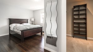 A bedroom with a wooden bed, a large mirror, and a built-in shelving unit. - G@Home Quiet 5BR4BA Retreat, Gateway to Banff & COP & Hwy 1 (Calgary)