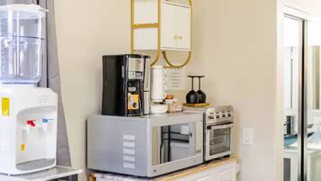 Een kleine keuken met een koffiezetapparaat, magnetron en waterdispenser.
