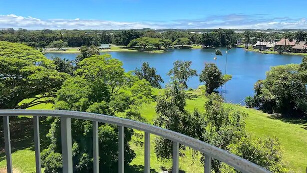 A view of a lake surrounded by lush greenery and trees, with a clear blue sky above. - Best View in Hilo - Pool, WIFI, 2 BD Condo (Hilo)