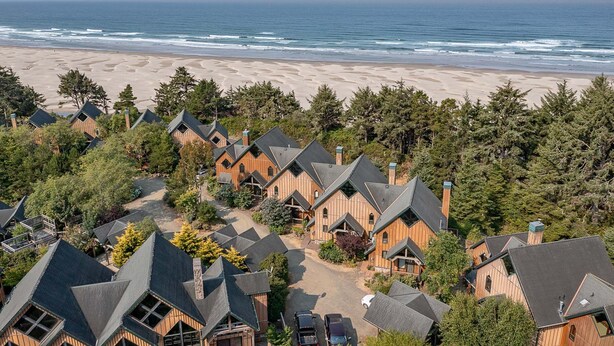 A coastal residential area with wooden houses, a beach, and a forested backdrop.