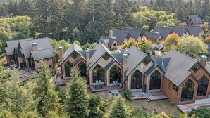 A cluster of log cabin-style cabins with pitched roofs and large windows, surrounded by dense forest.