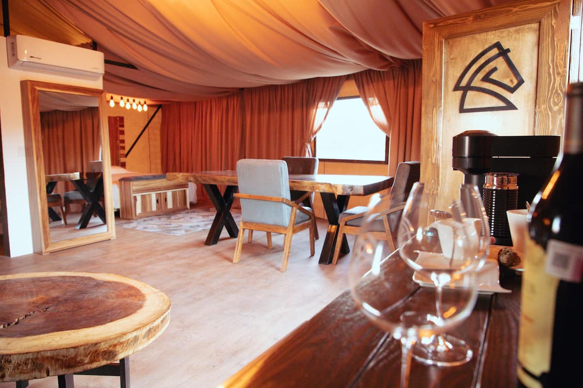 A cozy room with a wooden dining table, chairs, and a bar area with a wine glass.