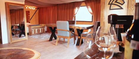 A cozy room with a wooden dining table, chairs, and a bar area with a wine glass.