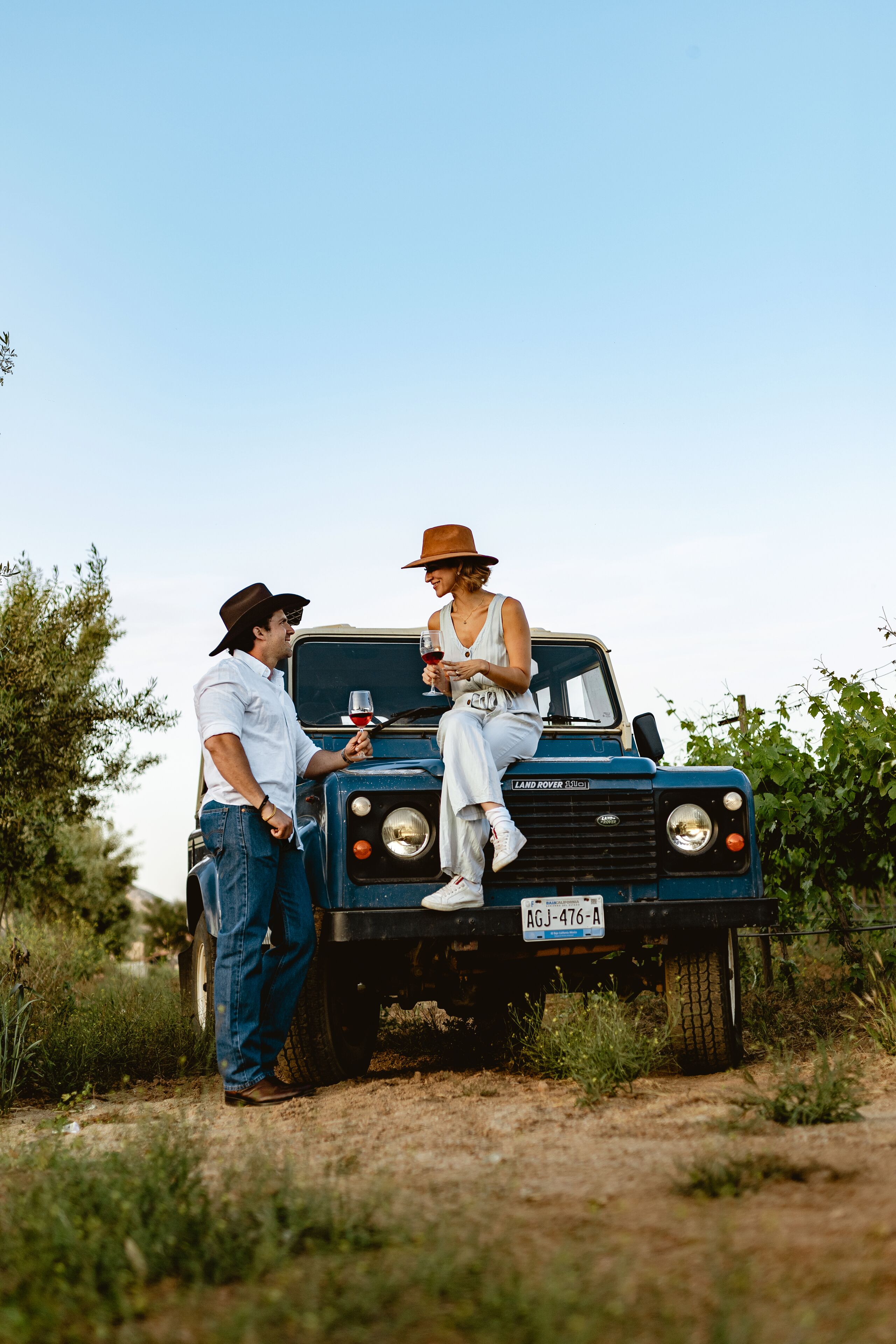 A vintage blue Land Rover with a license plate AGJ-476-A parked on a dirt path.