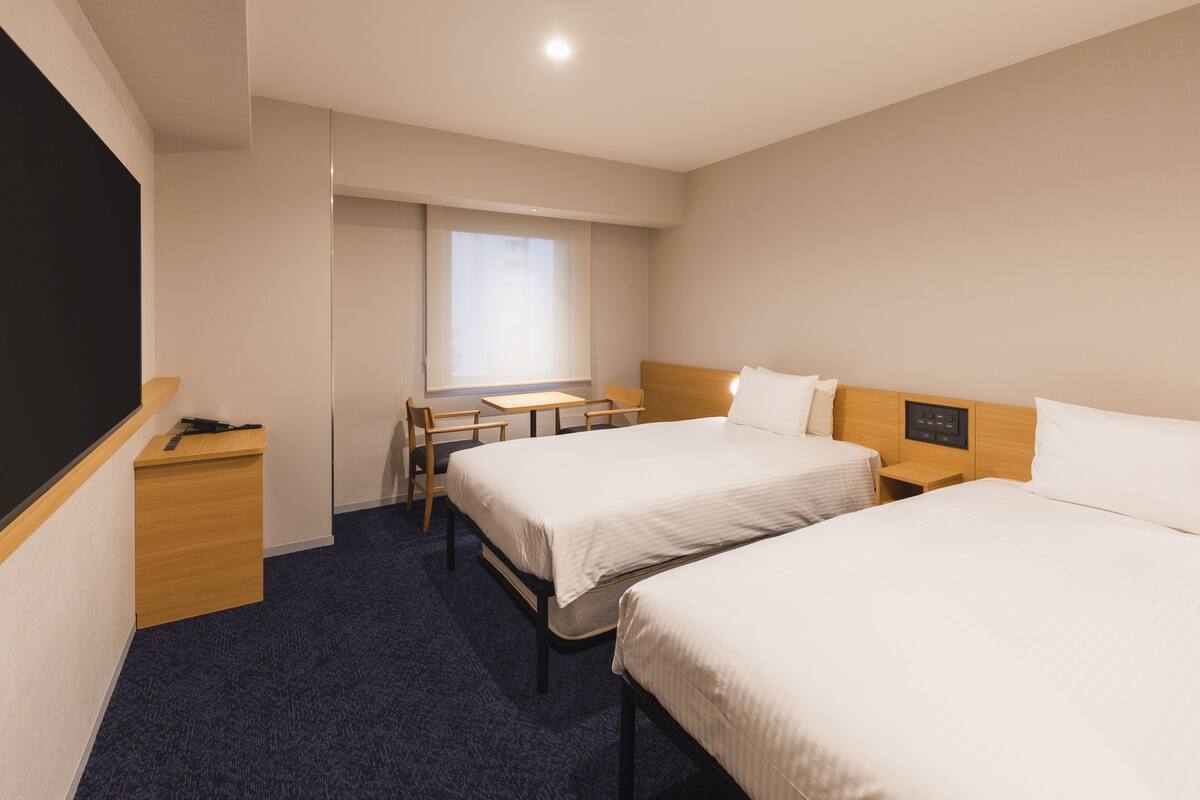 Habitación de hotel con dos camas, un escritorio y una silla.