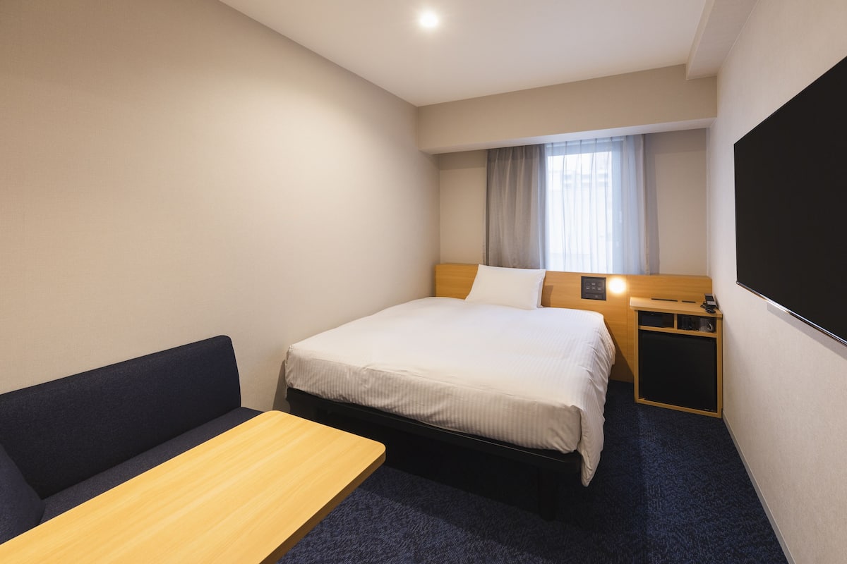Una habitación de hotel con una cama, un escritorio, una silla y un televisor.