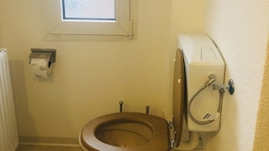 Ein kleines Badezimmer mit Toilette, einem Fenster und einer Duschkabine.