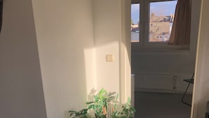 Ein Zimmer mit Blumentopf, Heizkörper und einem Vorhangfenster.