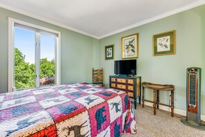 A bedroom with a large bed, a dresser, a television, and a radiator.