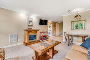 Una sala de estar con chimenea, televisor, mesa de comedor y sofá.