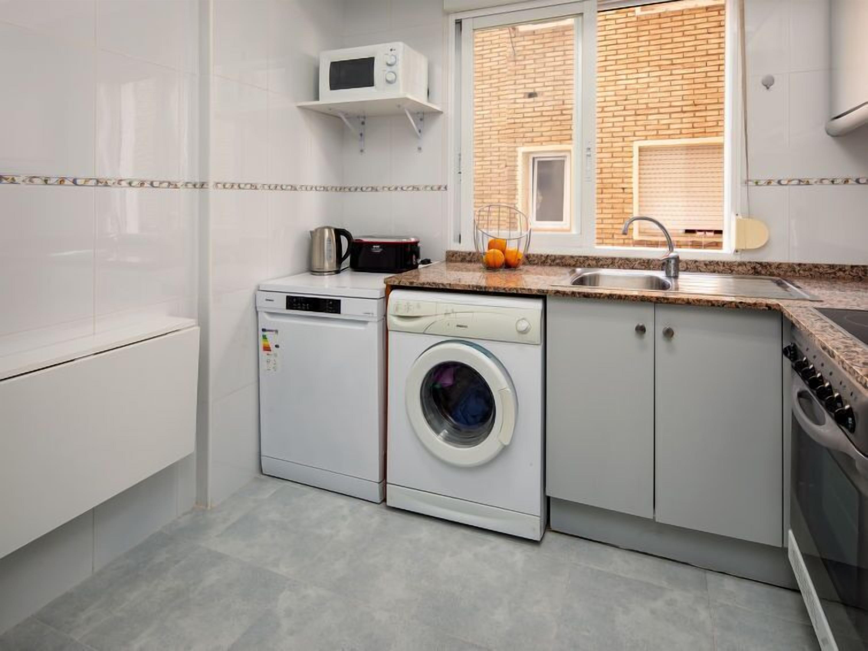 A compact kitchen with a washing machine, a microwave, and a sink.