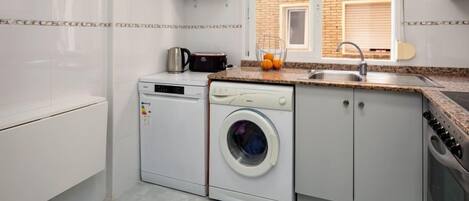 A compact kitchen with a washing machine, a microwave, and a sink.