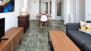 Un soggiorno moderno con un divano, un tavolino in legno, una TV e un'area pranzo con tavolo e sedie.