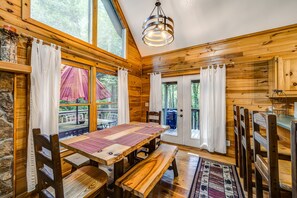 Cozy cabin interior with a dining table for four and large windows.