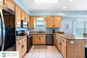 Une cuisine moderne avec des meubles en bois, des appareils en acier inoxydable et un sol carrelé.