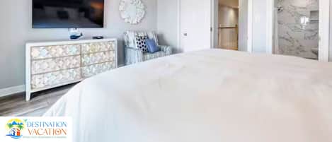 Un dormitorio moderno con una cama grande, un televisor de pantalla plana, un adorno de pared y un vestidor.