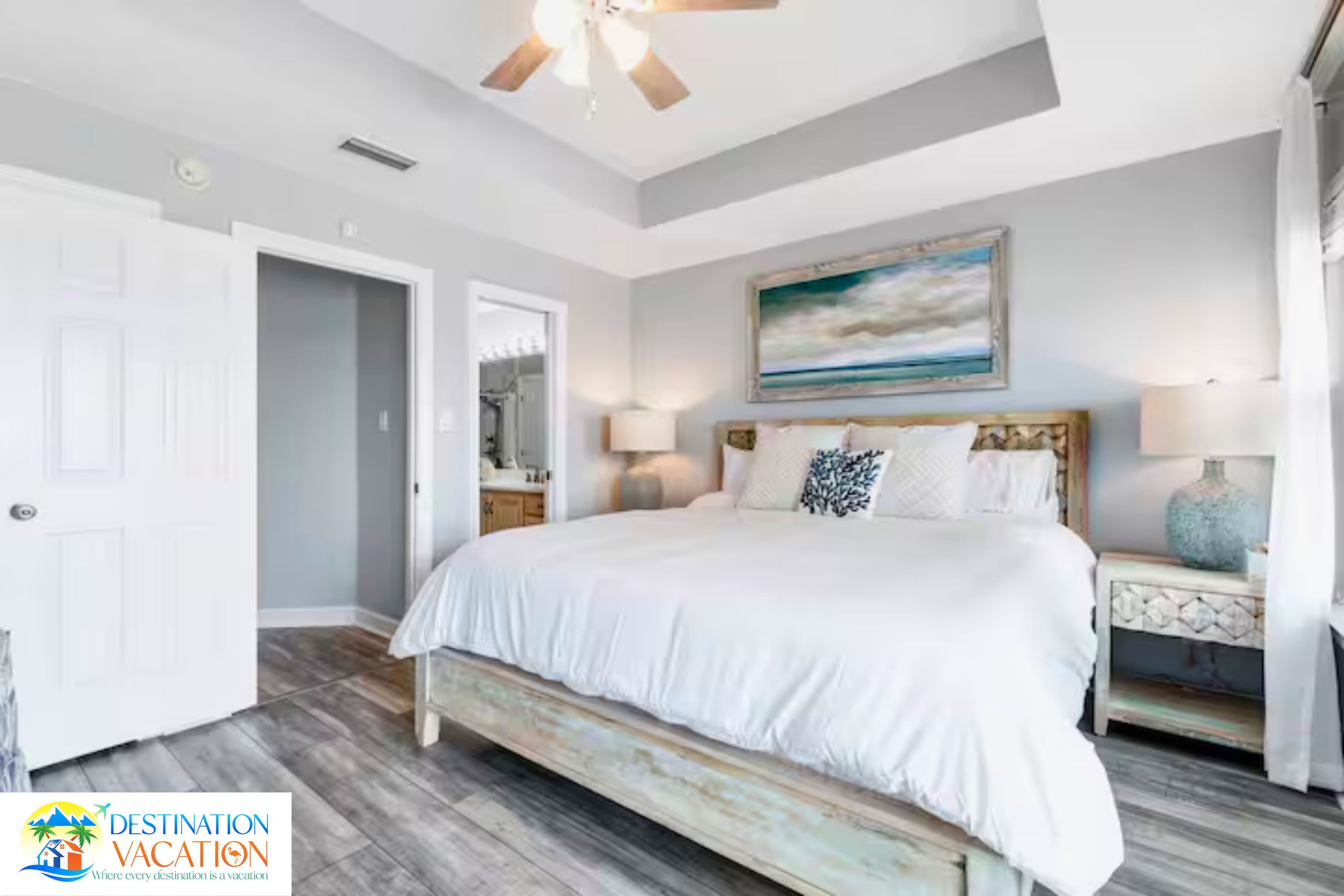 A bedroom with a bed, a ceiling fan, a painting, and a nightstand.