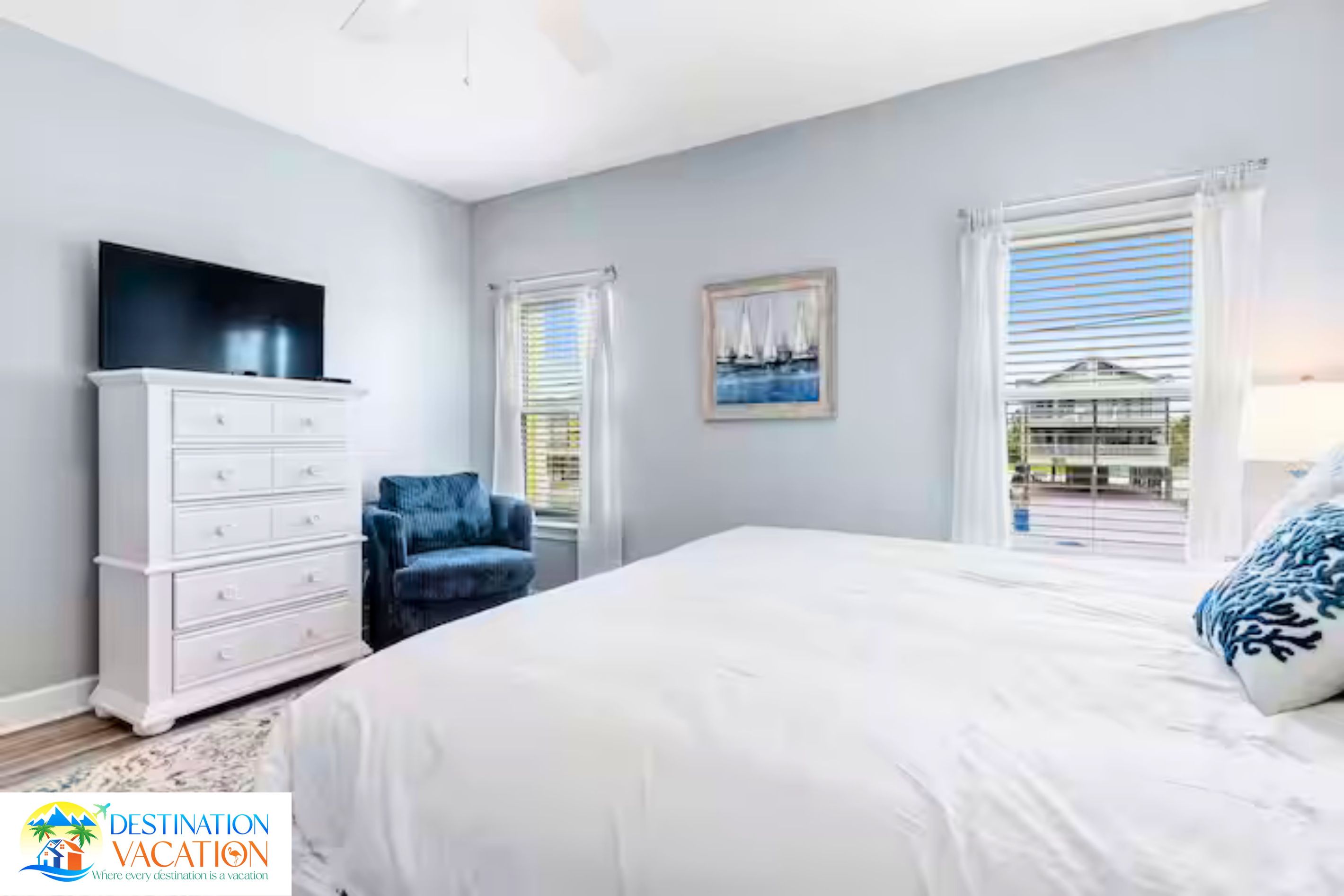 Une chambre à coucher avec un lit, une commode, une chaise, un tableau et une fenêtre donnant sur un beau paysage.