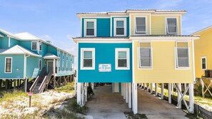 Une rangée de maisons de plage avec une enseigne indiquant « Sugar on the Shores » et un panneau indiquant l’accès à la plage.