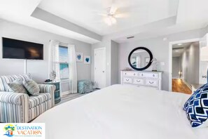 A bedroom with a large bed, a television, a dresser, and a mirror. - Gulf Shores Paradise: Beachfront 5BR + Pool + Views (Gulf Shores)