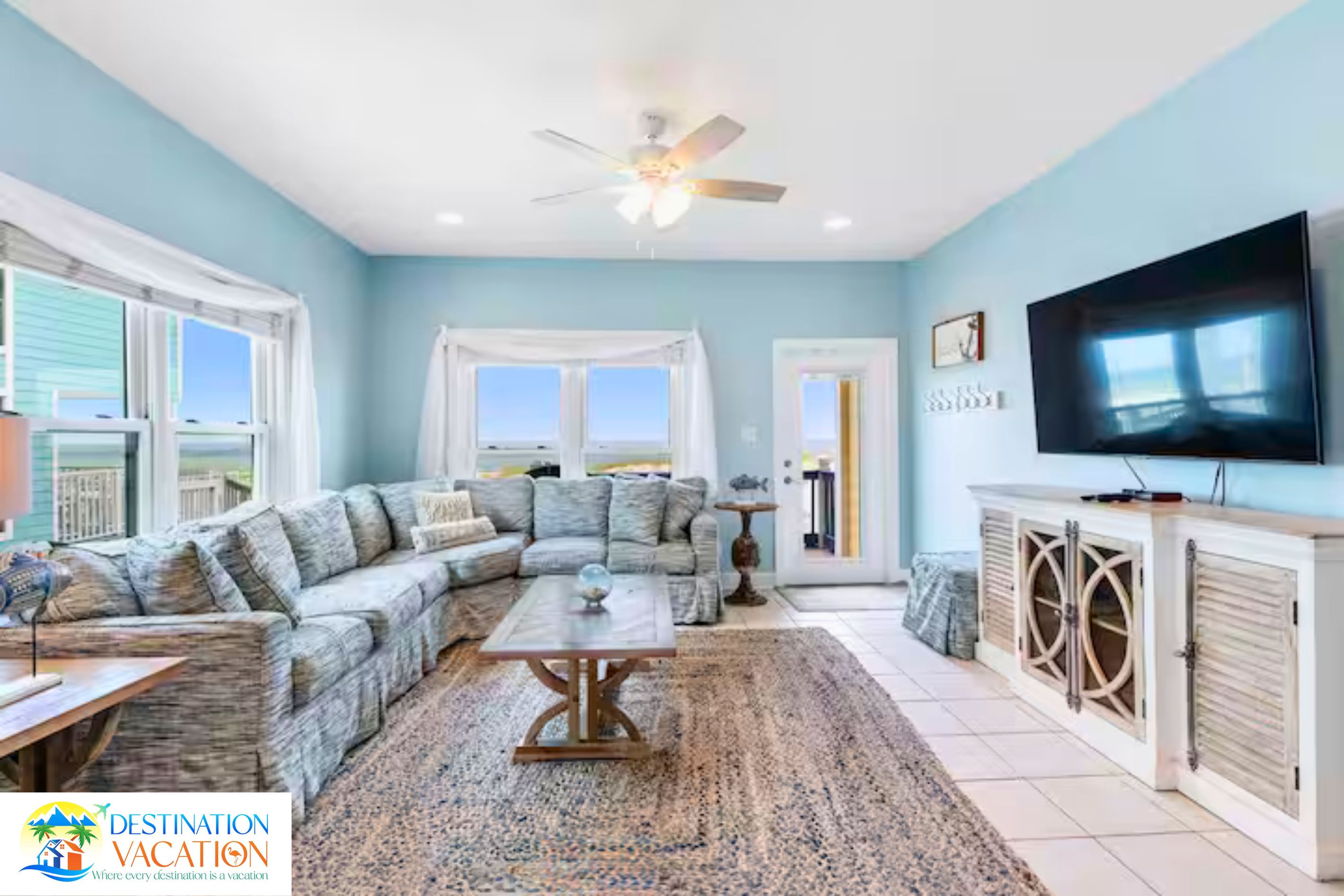 A living room with a sectional sofa, a coffee table, a TV, and a ceiling fan.
