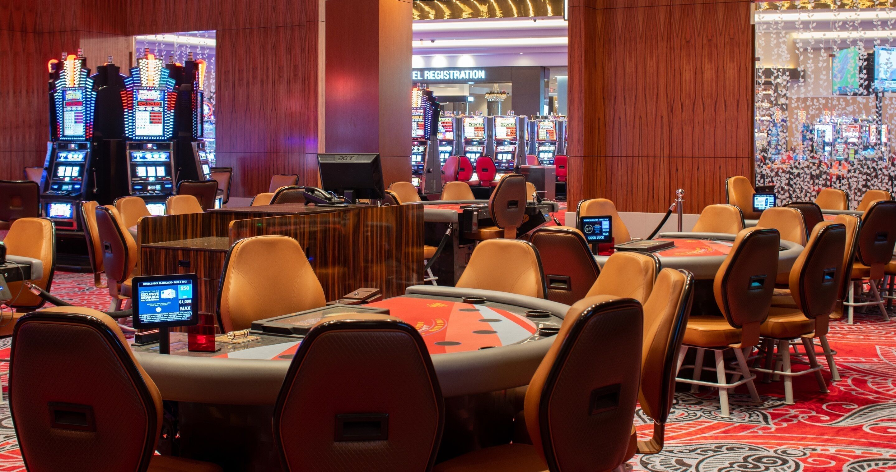 A casino area with blackjack tables, chairs, and slot machines.