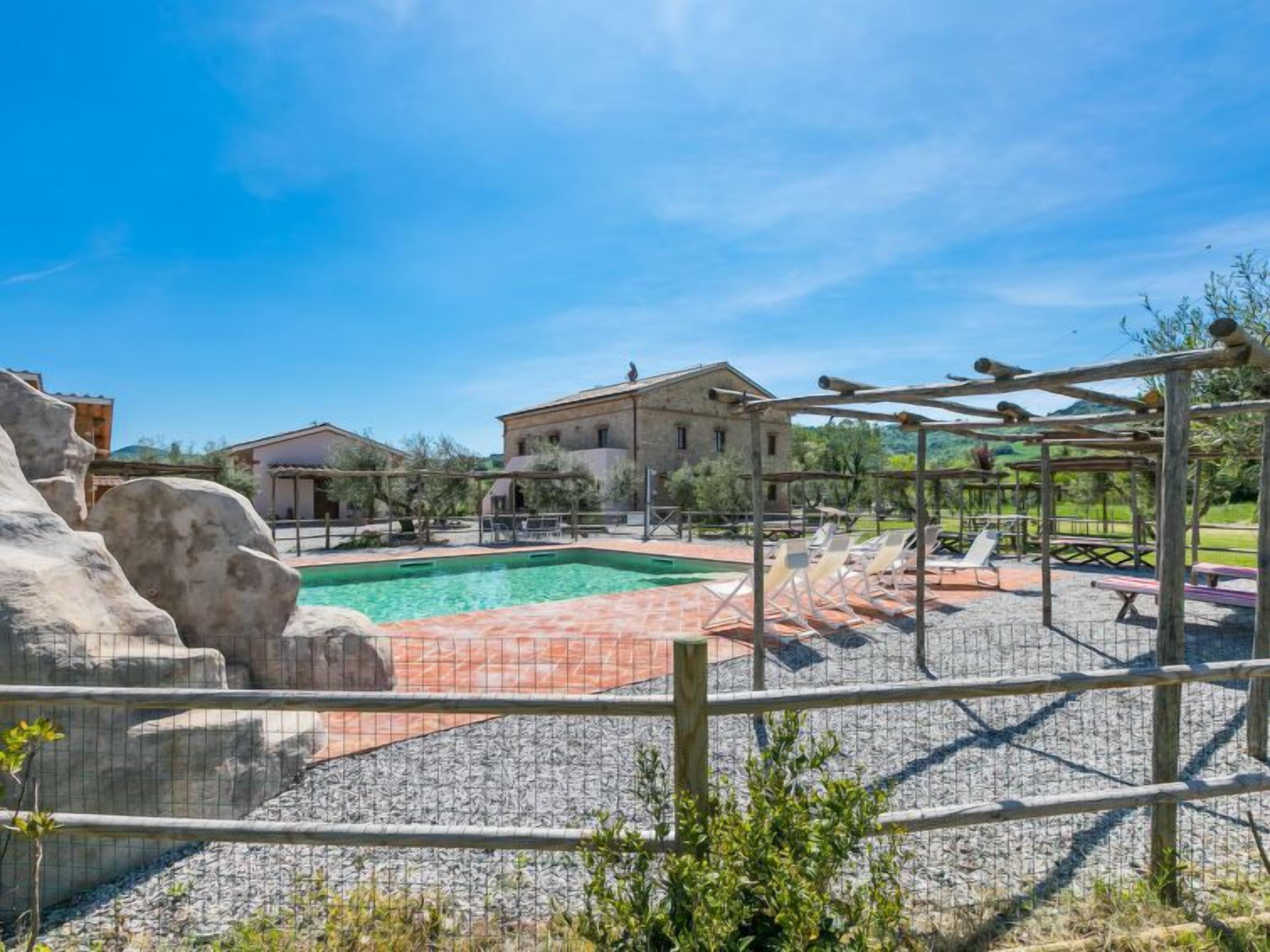 Ein Poolbereich mit Pergola, Liegestühlen und einer Steinmauer.