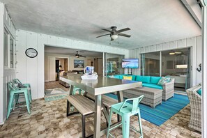 Un vaste espace de vie comprenant une grande table à manger, des chaises de couleur turquoise, un canapé et un téléviseur.