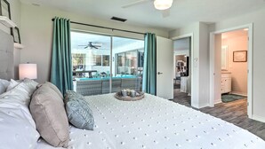 A spacious bedroom with a large bed, a ceiling fan, and a view of the outdoor area. - Bright & Breezy Cape Coral Retreat w/ Pool! (Cape Coral)