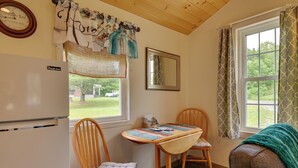 A cozy kitchen with wooden chairs, a table, and a refrigerator. - Quiet Country Escape: Fire Pit, Fish On-Site! (West Edmeston)