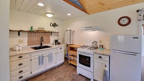 A kitchen with white cabinets, a wooden ceiling, a sink, a stove, and a refrigerator. - Quiet Country Escape: Fire Pit, Fish On-Site! (West Edmeston)