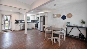 Una cocina moderna con armarios blancos, una zona de comedor con una mesa redonda y sillas, y una pared decorativa con diseños circulares.