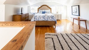 A bedroom with a wooden bed, a dresser, a nightstand, and a framed picture on the wall. - Contemporary 3-Bedroom Home with Balcony in RVA (Richmond)