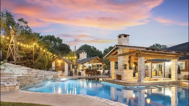 A poolside area with stone structures, outdoor seating, and string lights.