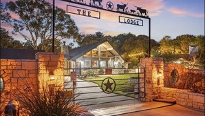 A lodge entrance with a stone wall, a metal gate, and a sign above.