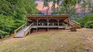Eine Holzterrasse mit einer Treppe zu einer Aussichtsplattform, umgeben von Bäumen.