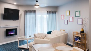 Una sala de estar moderna con una televisión de pantalla plana, una chimenea, un sofá, una mesa de comedor y una mesa de centro.